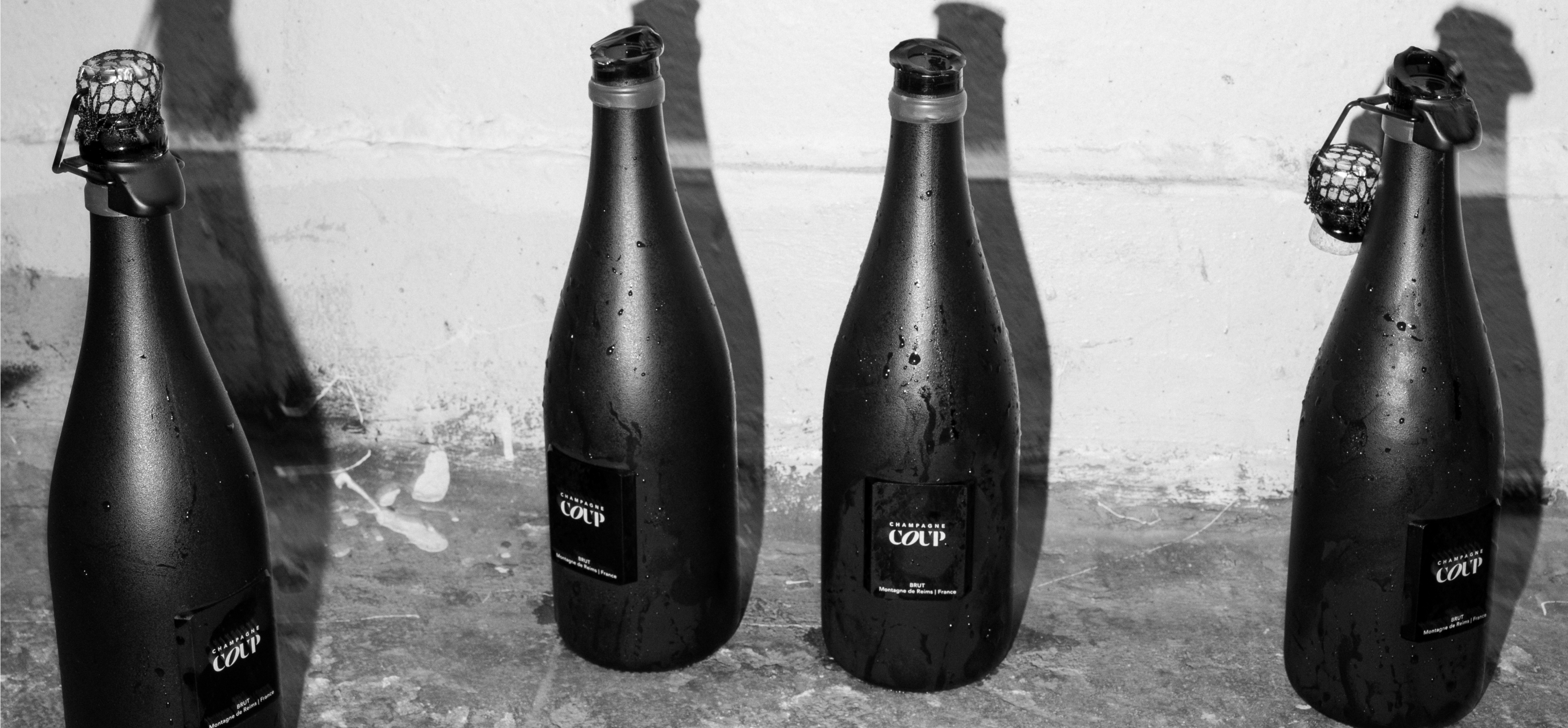 Four black bottles with 'COVP' labels on a concrete surface.