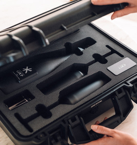  Open COUP gift case with matte black bottle, flutes, saber, and card inside.